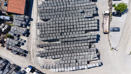 Vis&atilde;o a&eacute;rea de blocos de concreto organizados em p&aacute;tio industrial, evidenciando produ&ccedil;&atilde;o em escala, log&iacute;stica de materiais e infraestrutura da ind&uacute;stria da constru&ccedil;&atilde;o.
