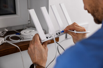 Wireless internet. Service technician connecting ethernet cable to Wi-Fi router at home