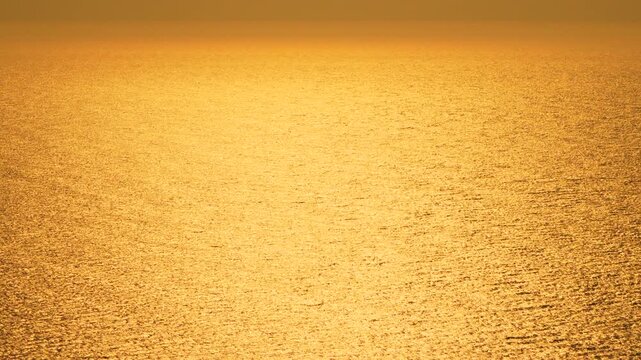 Golden sunset ocean water shimmering surface creating abstract background texture during beautiful dusk or dawn.