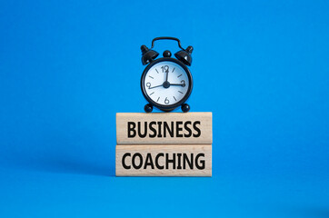 Business Coaching symbol. Wooden blocks with words Business Coaching. Beautiful blue background with alarm clock. Business and Business Coaching concept. Copy space.