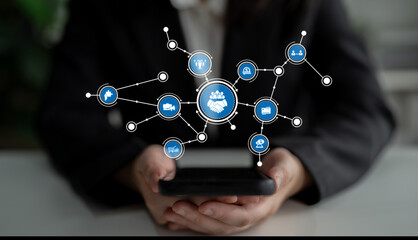 A person holds a smartphone surrounded by icons illustrating digital connections and networking, symbolizing modern communication and collaboration in a business setting. Tessel