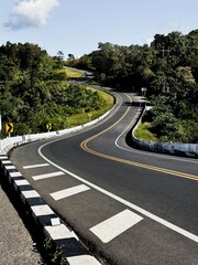 Winding mountain road through lush green forest under a clear blue sky