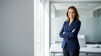 Beautiful hispanic senior business woman with crossed arms smiling at camera. European or latin confident mature middle age leader female businesswoman standing at office workplace, copy space. 