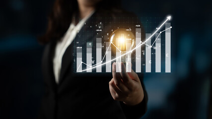 A businesswoman presents a glowing light bulb alongside financial growth charts, symbolizing innovative ideas and success in a dynamic corporate environment. Impute