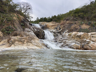 Waterfall flows over rocks in a natural setting near trees