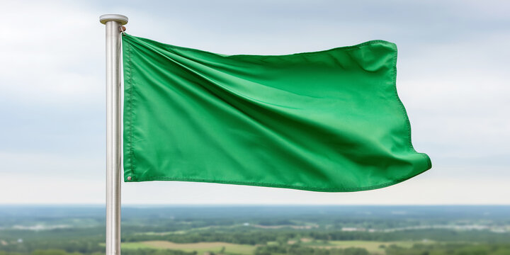 Green flag flying high on a flagpole against a scenic background, providing copy space for text