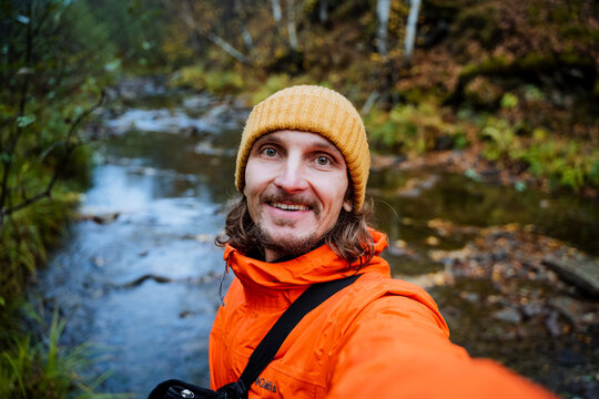 vibrant outdoor storytelling, male vlogger in vibrant attire amidst natural landscape elements, expressive traveler sporting bright clothing captured against dynamic outdoor natural features