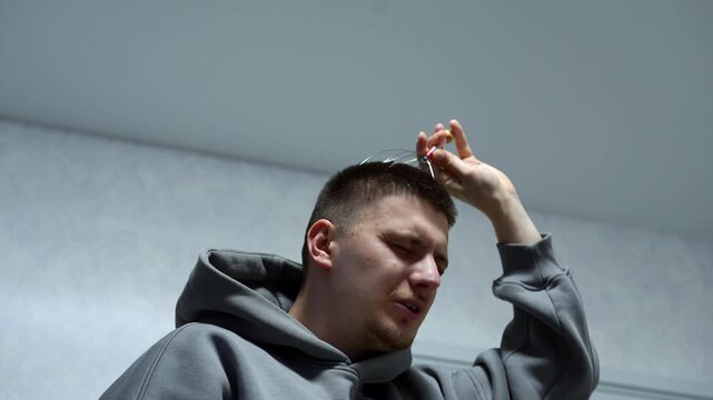A man gives himself a relaxing head massage.
A man scratches his head with a head massager.
Health and body care.
A relaxing massage that brings pleasure. Head, massage, body, massager, man, hair