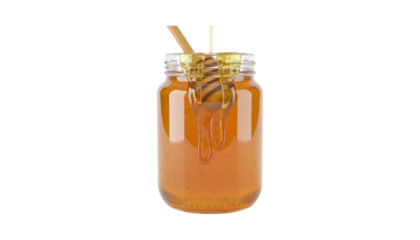 Glass jar of golden honey with a wooden dipper submerged inside, as viscous amber liquid drips from the spoon and pours from above in a delicious, sticky stream