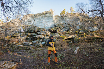 Outdoor explorer examines scenic landscape, Individual observing layered cliffs with sparse pine trees, Adventurer in bright clothing scouting pathway near rugged limestone formations