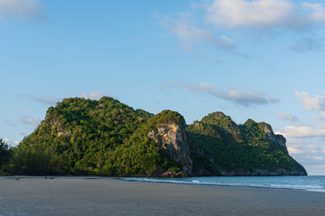 Serene Beach Landscape with Lush Green Mountains Under Blue Sky