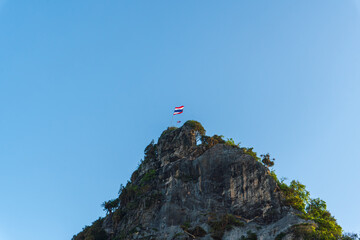 Flag of Thailand on Rocky Peak Against Clear Blue Sky