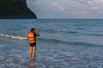 Boy Wearing Life Jacket Standing in Shallow Beach Water