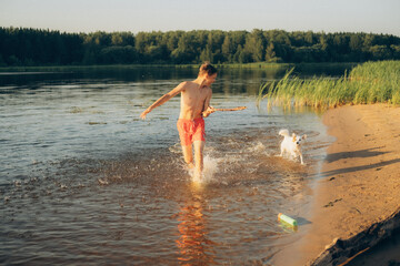 Boy Playing with Dog in Water at Lakeside Beach
