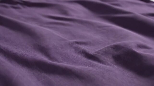 Closeup of flowing purple fabric showcasing its soft texture and elegant drapes perfect for backgrounds and textile designs.
