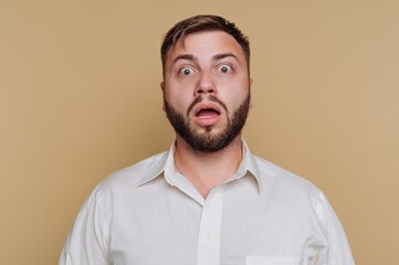 Obraz premium Man shows surprise with wide eyes and open mouth in a studio setting with a brown background during daytime