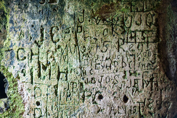 Words and letters carved into an ancient stone wall