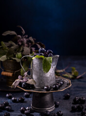 Blueberries in rustic metal pitcher with sage leaves