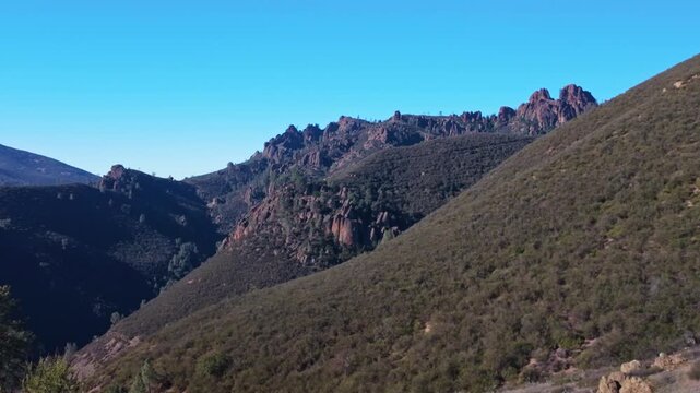 Vibrant green rolling hills and chaparral covered slopes seen from a winding hiking trail in Pinnacles National Park