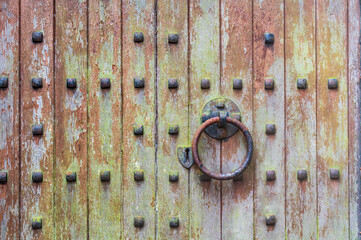 An ancient wooden door with an iron door handle and keyhole