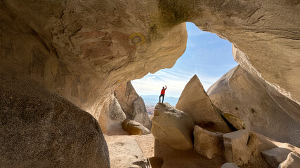 Explorer Standing Inside a Majestic Natural Rock Arch