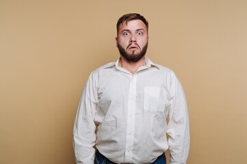 Fototapeta premium Man standing with surprised expression against plain background in indoor setting during daytime