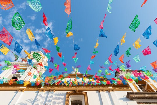 Vibrant Papel Picado Above Festive Building Architecture against a Blue Sky
