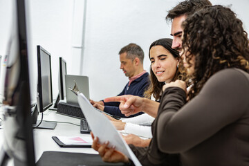Collaborative workspace with four people engaged in discussion and work on computers