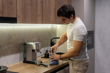 Man in white shirt scooping coffee by espresso machine