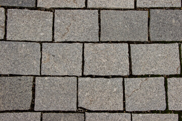 Obraz premium Textured gray stone pavers arranged in a geometric pattern, showcasing the natural variations and imperfections of the surface in an outdoor setting with earthy tones