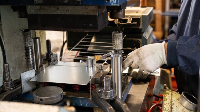 Worker using press plate removal tool during metal stamping machine setup