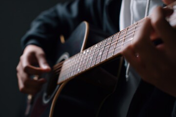Fototapeta premium Young adult playing acoustic guitar close-up