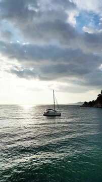 Aerial drone view, flying over the sea and sky with clouds at sunset with lonely boat sailing at Mediterranean, vertical nature background	