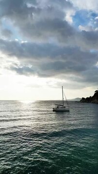 Aerial drone view, flying over the sea and sky with clouds at sunset with lonely yacht sailing at Mediterranean, vertical nature background	
