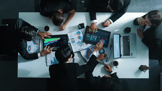Time lapse of business people analyze financial chart at meeting. Top down aerial view of smart people looking at statistic graph with stock market data document scatter at meeting table. Directorate.