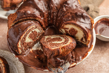 Chocolate marble bundt cake or zebra cake with chocolate glaze sliced on brown table background, close up