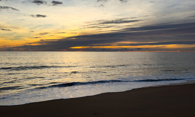 Blurred Background of Serene Sunset Over Calm Ocean Wave at Coastal Beach with Gentle Footprints in Soft Sand Landscape. Blurry Background For Design Projects.