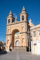 Fototapeta premium Knisja tal-Madonna ta' Pompei church in the coastal village of Marsaxlokk with Christmas tree lights, palm trees, and deep blue sky Marsaxlokk, Malta