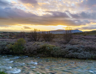 Arctic tundra river at dusk with mountain backdrop