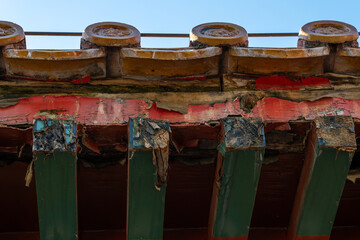 Naklejka premium Detail texture of peeling paint and weathered wood on the eaves of a historic Chinese building.