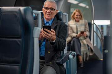 Mature man using mobile phone traveling on public transport