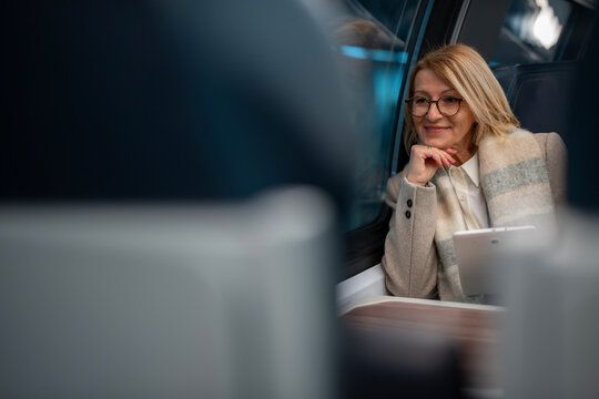 Mature woman traveling by train looking out window