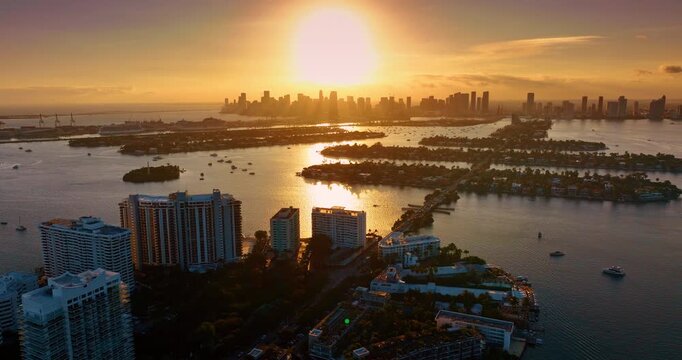 Beautiful golden setting sun lights the scenery of Miami, Florida, USA. Biscayne Bay with numerous boats on. Brickell Key at sunset. Drone footage.