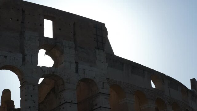 Silhouette of the colosseum in rome against bright sky. Majestic silhouette of the roman colosseum's ancient arches and ruins standing against a bright, clear sky, showcasing its architecture