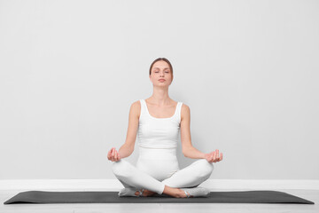 Fototapeta premium Pregnant woman practicing yoga on mat indoors