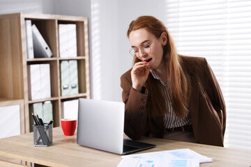 Obraz premium Sleepy woman yawning at workplace in office