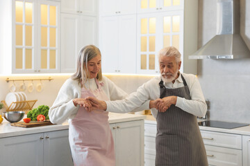 Happy senior couple dancing while cooking in kitchen