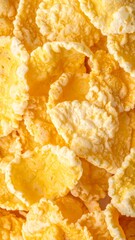 Close-up view of golden yellow cornflakes, showing their crispy texture and irregular shapes, ready for a delicious breakfast meal.