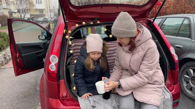 Enjoying a Cozy Car Picnic with Mother and Daughter during Winter Season