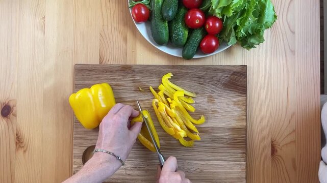 Carefully Chopping Yellow Bell Pepper to Prepare for a Fresh Salad